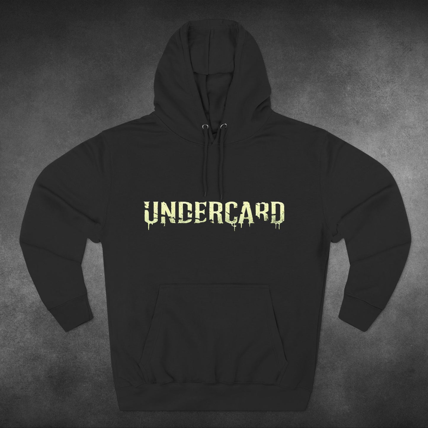  The front of a black hoodie featuring the word "Undercard" in bold, dripping neon-green letters across the chest. The design is simple and striking, offering a minimalist yet edgy look. The hoodie is displayed on a textured grey background