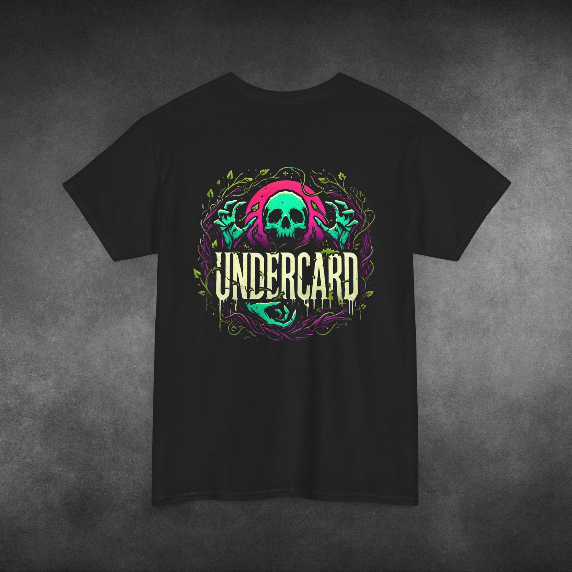 Text Description: A black t-shirt featuring a bold graphic of a neon green and pink skull surrounded by twisted vines, with the word "Undercard" in stylized, dripping white text beneath the skull. The vibrant design has a dark, edgy aesthetic, set against a textured grey background.